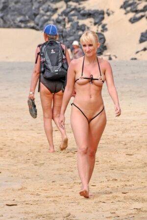 Hot blonde removes a skimpy bikini during a visit to a public beach on picsofsex.com