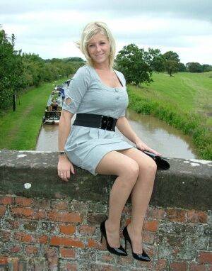 Blonde female sits atop a bridge in a dress and nylons with shiny pumps on picsofsex.com