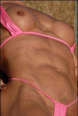 Middle-aged bodybuilder Emery Miller releases her boobs from a pink bikini on picsofsex.com