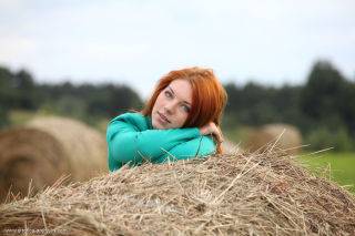 Redhead amber a poses on the stack of hay baring her smooth pussy on picsofsex.com